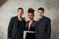 One beautiful african american woman standing with two handsome men, smiling. Elegant style. Studio background. Royalty Free Stock Photo