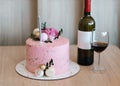 Pink cake, a bottle of wine and a glass on the table. Royalty Free Stock Photo