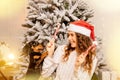 One beautiful curly-haired girl sits with a puppy near the Christmas tree, New Year`s photo session with candy lollipop Royalty Free Stock Photo