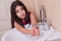 One beautiful little middle eastern arab girl with red dress is washing her hands in the bathroom.