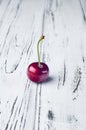 One beautiful red cherries on a white wooden table