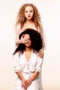 One girl closes the other`s eyes. Afro and Blond Royalty Free Stock Photo