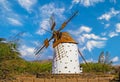 One beautiful spanish isolated ancient white traditional stone windmill, brown wood wings against blue sky, few scattered fluffy Royalty Free Stock Photo