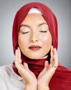 One beautiful young muslim woman with eyes closed wearing red headscarf and lipstick against grey studio background Royalty Free Stock Photo