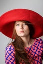 One beautiful young woman blowing a kiss in red blue dress and a hat isolated white grey background . Studio shot, vertical image Royalty Free Stock Photo