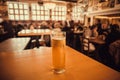 One beer glass on table of busy bar, with crowd of people. Interior of pub with fresh lager beer inside Royalty Free Stock Photo