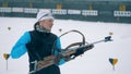 One biathlete aims with a rifle, then puts it on a back and smiles at a camera. 4K