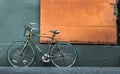 One bicycle in front of steel orange door with green wall of warehouse