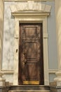 one big closed old brown wooden door on a white gray concrete wall Royalty Free Stock Photo