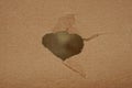 gray hole in a piece of brown paper cardboard Royalty Free Stock Photo