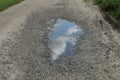 One big puddle on the road in gray earth