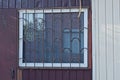 One big square window behind a brown iron grating on the wall Royalty Free Stock Photo