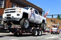 One big white chevy truck on a tow truck in the fourth of July parade