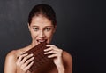 One bite is never enough. Studio shot of an attractive young woman biting into a slab of chocolate.