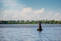 One black buoy on a calm water surface. Warning sign on the water on a sunny day