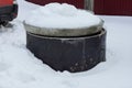 One black concrete circle covered with a gray lid stands in a snowdrift