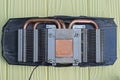 one black disassembled video card with a gray metal radiator and copper brown cooling pipes