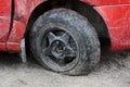 Black flat tire of a red car on a dirt road Royalty Free Stock Photo