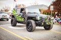 One black and green jeep driving through a Christmas parade