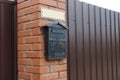 One black iron mailbox on a brown brick wall