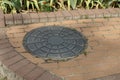 One black iron manhole lying on a brown sidewalk Royalty Free Stock Photo