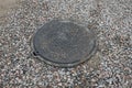 One black iron sewer manhole among gray fine rubble