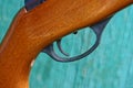 Iron black trigger on brown rifle on green background Royalty Free Stock Photo