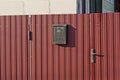 One black mailbox hanging on a red metal fence Royalty Free Stock Photo