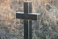 One black marble cross on an old grave in a cemetery