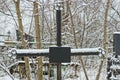 One black metal cross on a grave in a winter cemetery