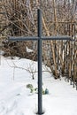 one black metal cross on a grave in a winter cemetery