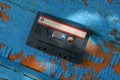 black old audio cassette is lying on a blue scuffed board