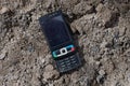 One black old mobile phone lies on gray earth