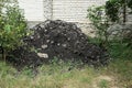 One black pile of pieces of asphalt in green grass