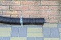 one black plastic drain pipe near a brown brick wall on the sidewalk Royalty Free Stock Photo