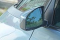 one black plastic mirror next to the glass of a gray passenger car