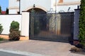 Black private metal gates with a wrought pattern on the street near the gray pavement