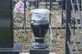 one black stone vase covered with white cellophane stands on the grave