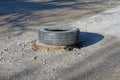 One black tire with a sewer pit on the gray asphalt