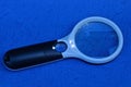 Black white plastic magnifier with light on a blue table Royalty Free Stock Photo