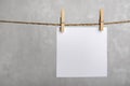 One blank square note paper card hanging with wooden clip or clothespin on rope string peg. Copy space Royalty Free Stock Photo