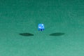 One blue dice falling on a green table
