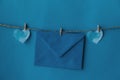 One blue envelope hanging on rope isolated blue background with two blue hearts on the sides. Write a letter to a friend.