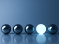 One blue glowing light ball standing out from the metal sphere balls on dark blue background