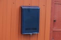 One blue iron mail box hanging on a red metal fence Royalty Free Stock Photo