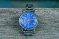 Blue old shabby watch with a metal strap on a gray table Royalty Free Stock Photo