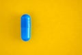 one blue pill capsule  on yellow background, close-up, top view, copy space Royalty Free Stock Photo