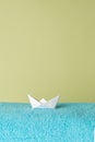 One blue towel on a green background with an origami boat. Royalty Free Stock Photo