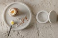 One boiled egg in stoneware egg cup with egg shell broken pieces in concrete tray, salt flakes in white concrete bowls Royalty Free Stock Photo