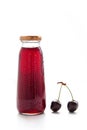 one bottle of cherry juice and two ripe cherry on white background Royalty Free Stock Photo